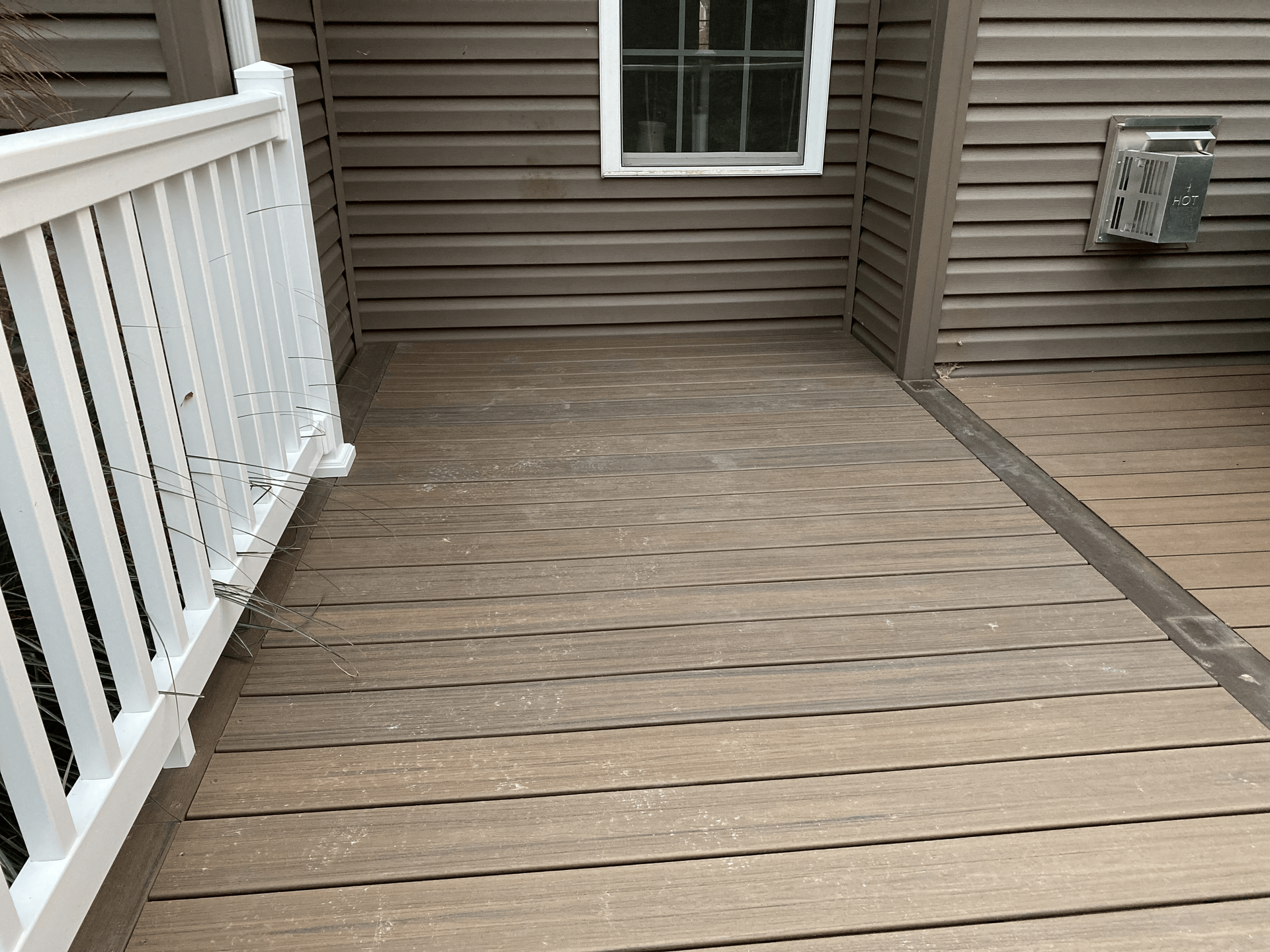 A wooden deck with a white railing next to a house.