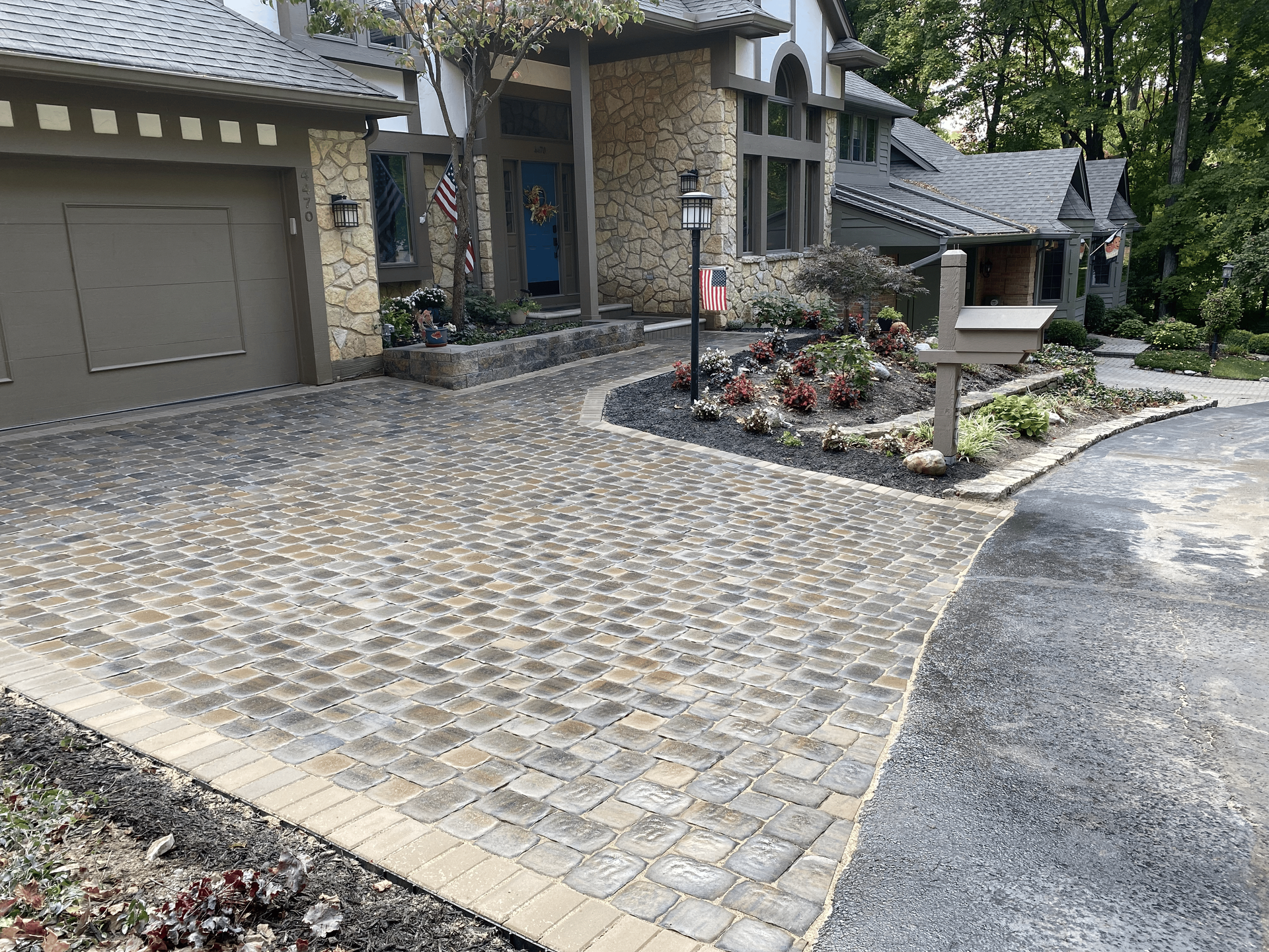 A driveway leading to a house with a brick driveway and a garage.