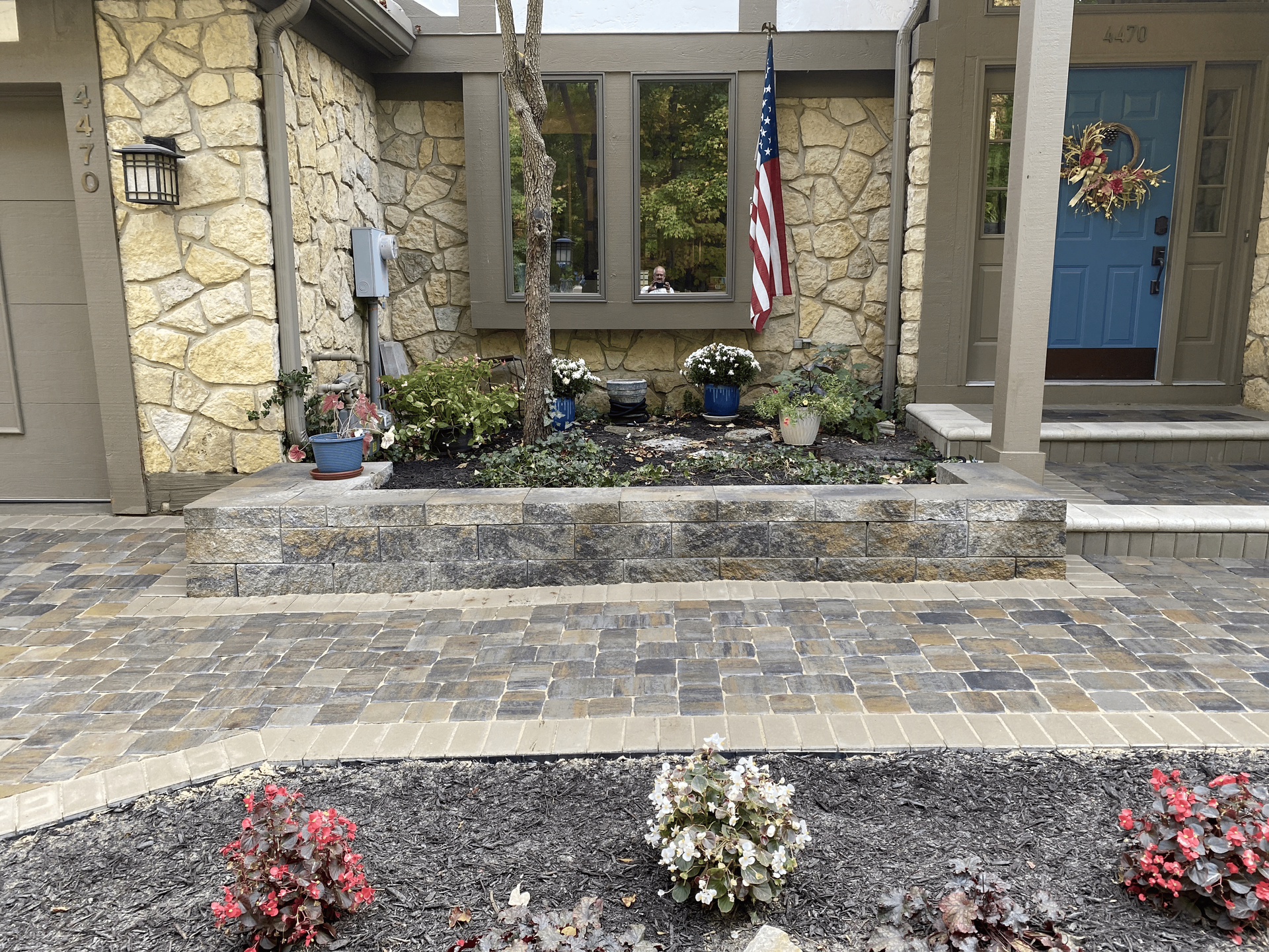 A stone house with a blue door and a garden in front of it.