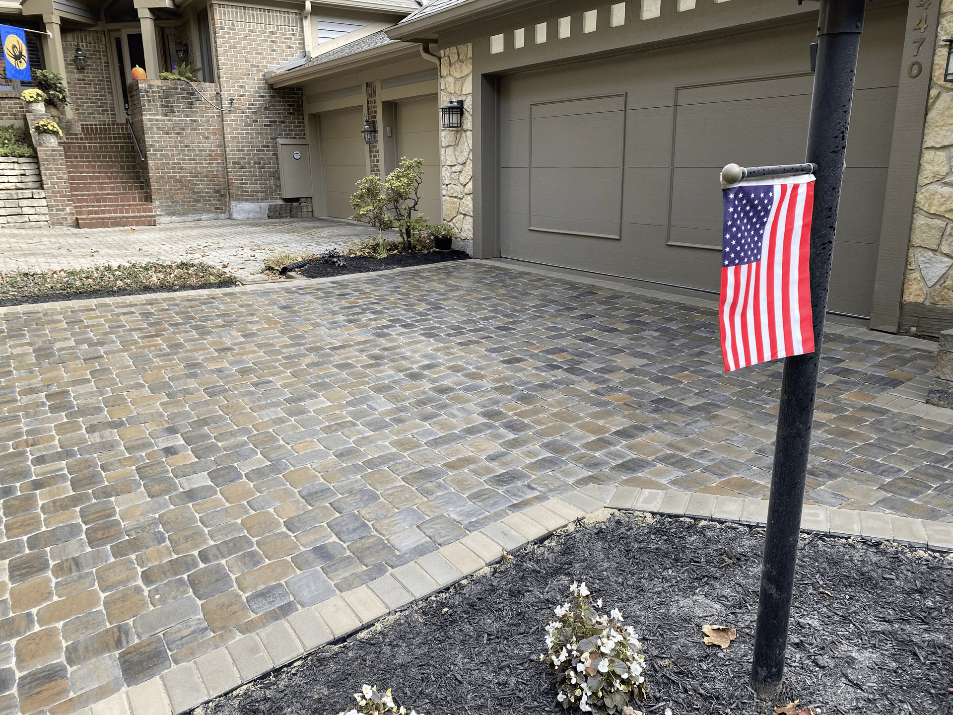 An american flag is hanging from a mailbox in front of a house.