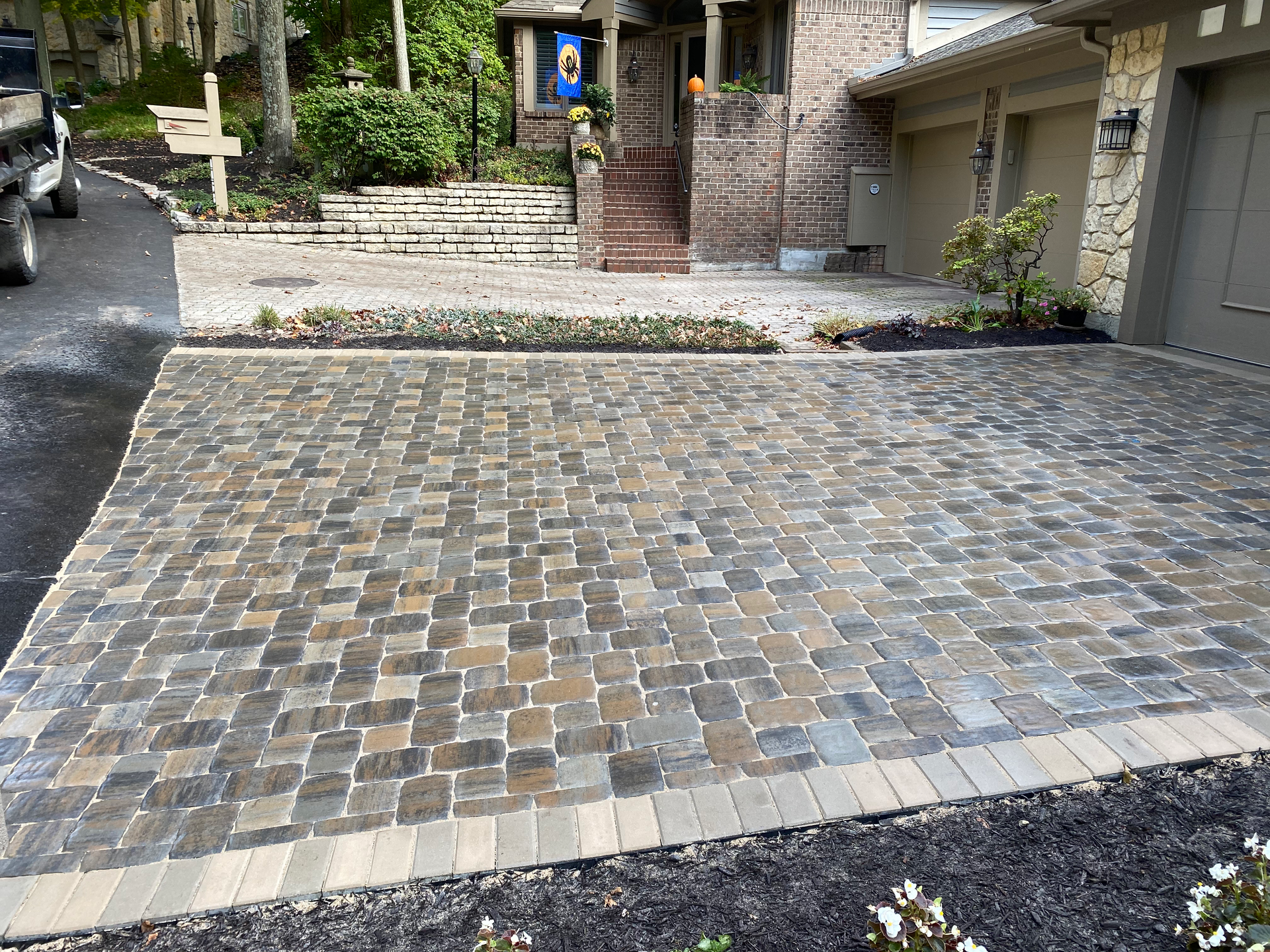 A brick driveway with a car parked in front of a house.