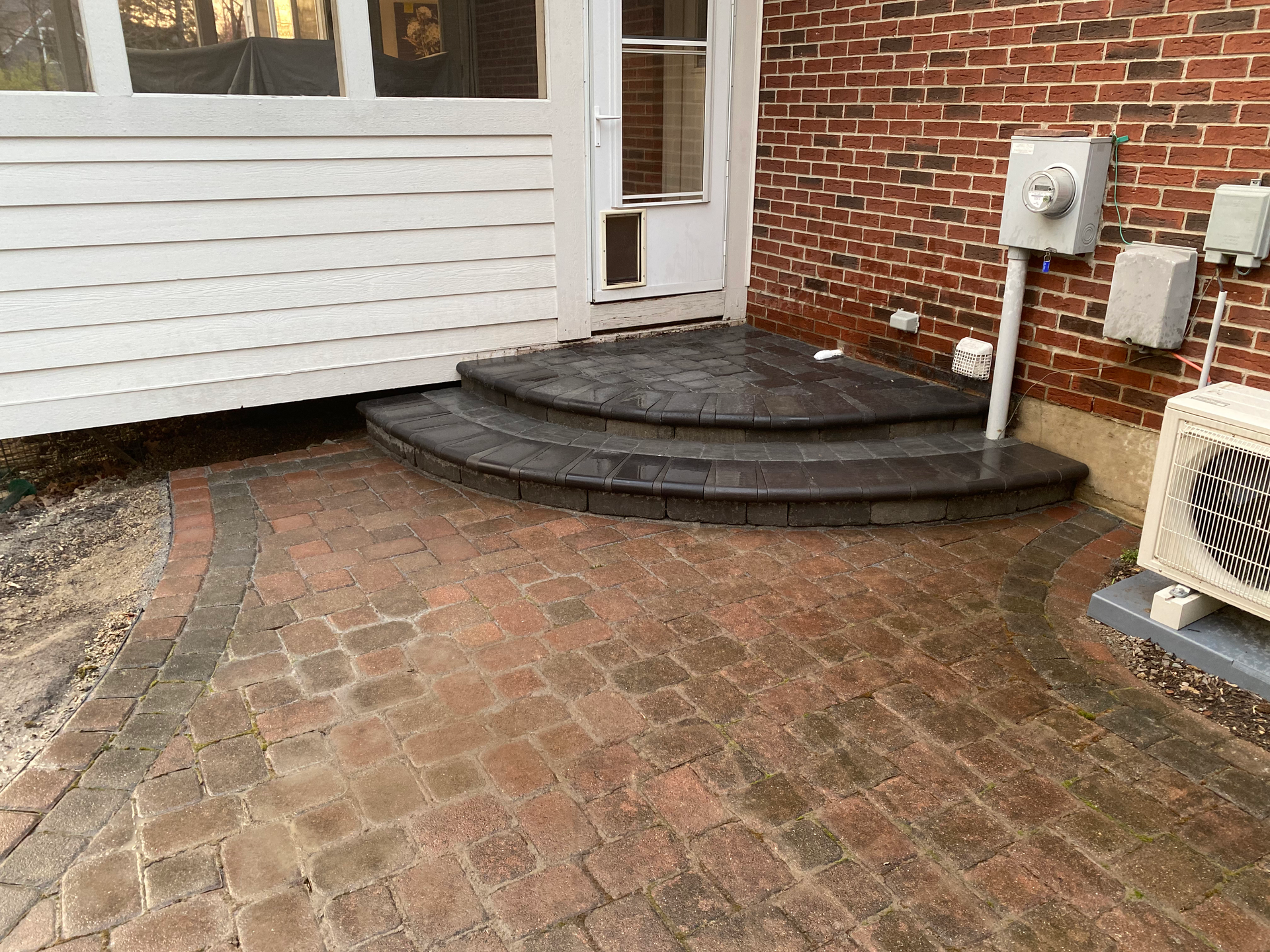 A brick patio with steps leading up to a brick building.