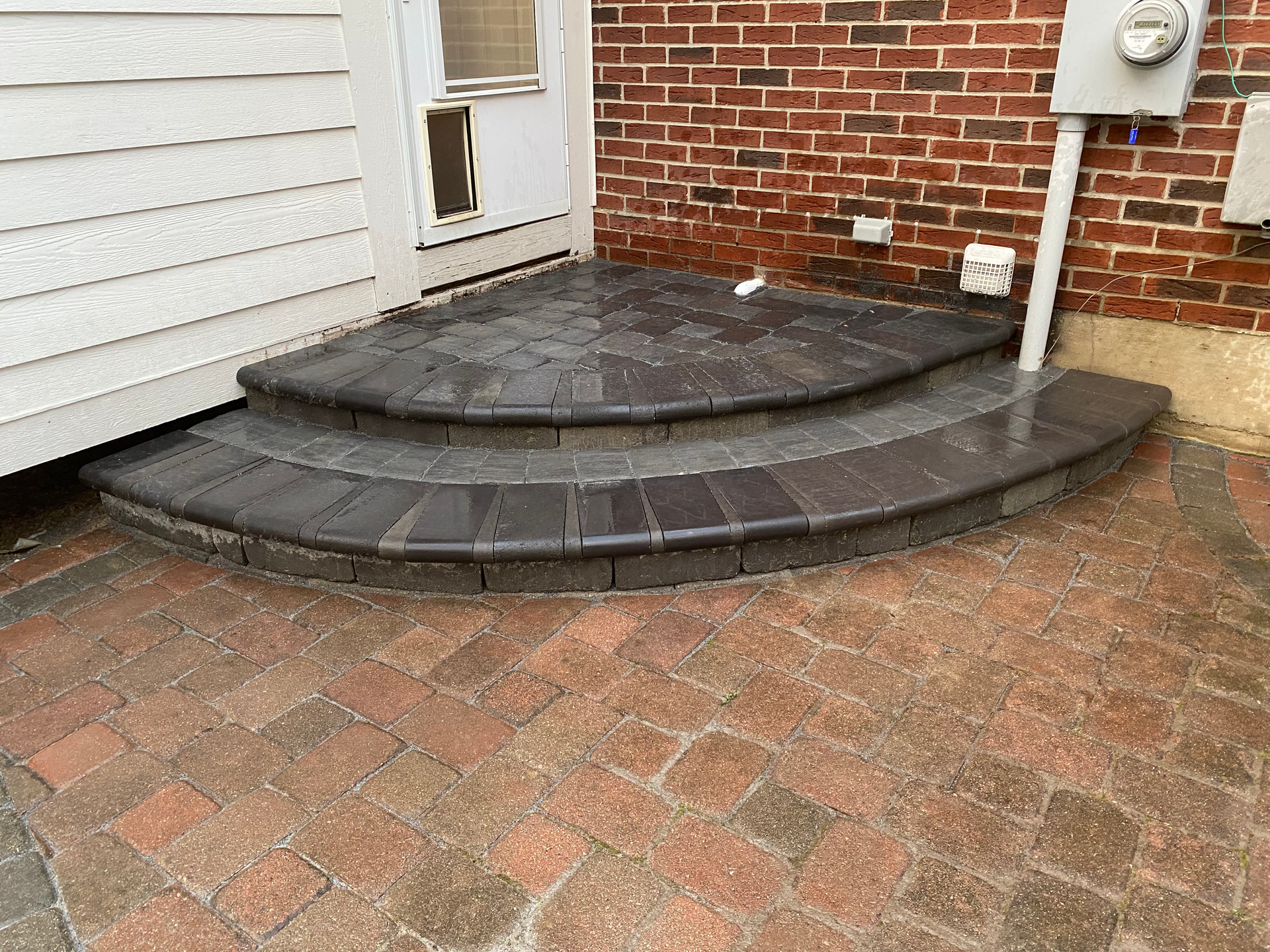 A brick walkway with steps leading to a brick house.