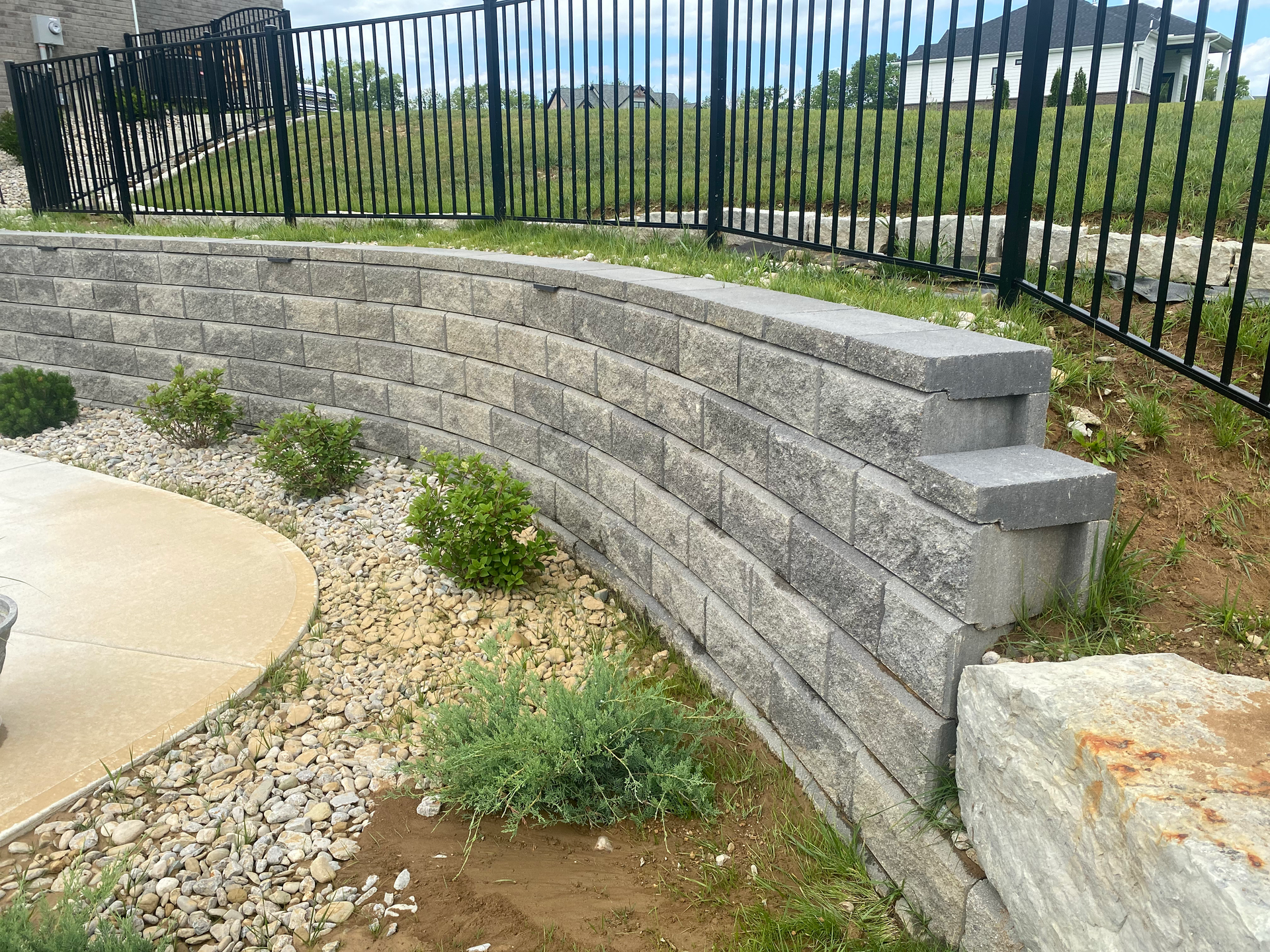 A brick wall with steps leading up to it and a fence in the background.