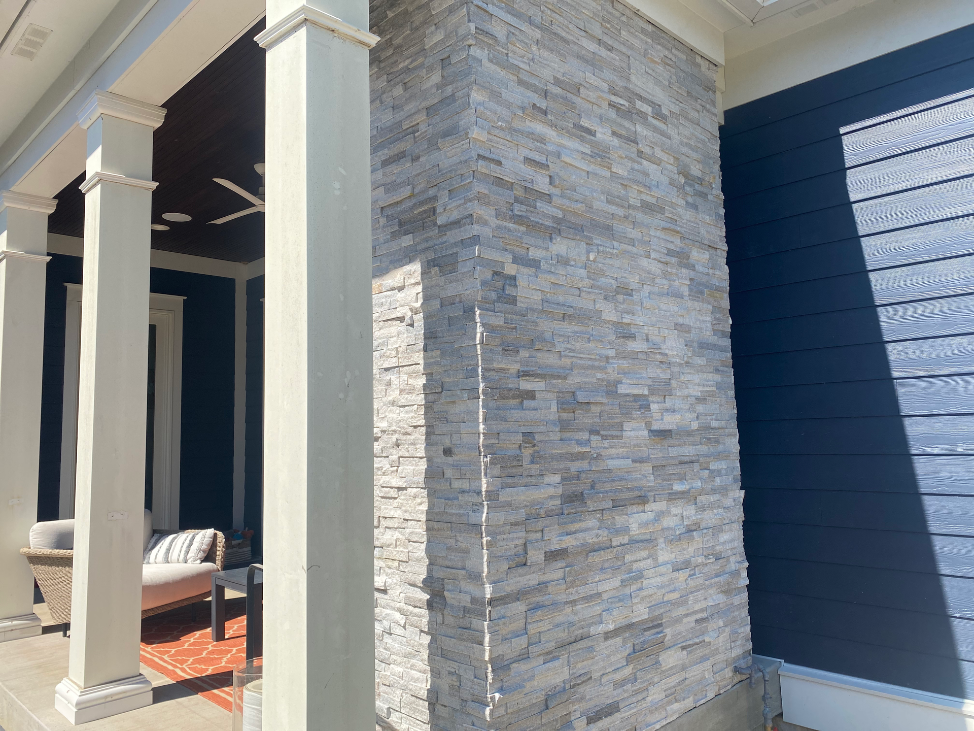 A blue and white house with a stone wall and columns.
