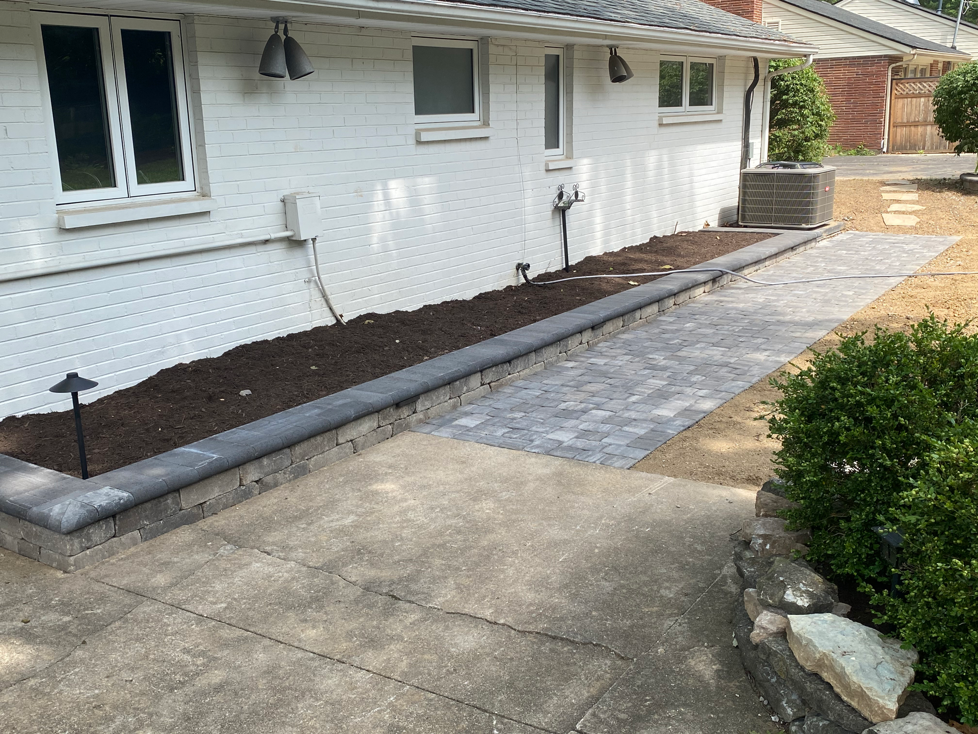 A walkway is being built in front of a white brick house.
