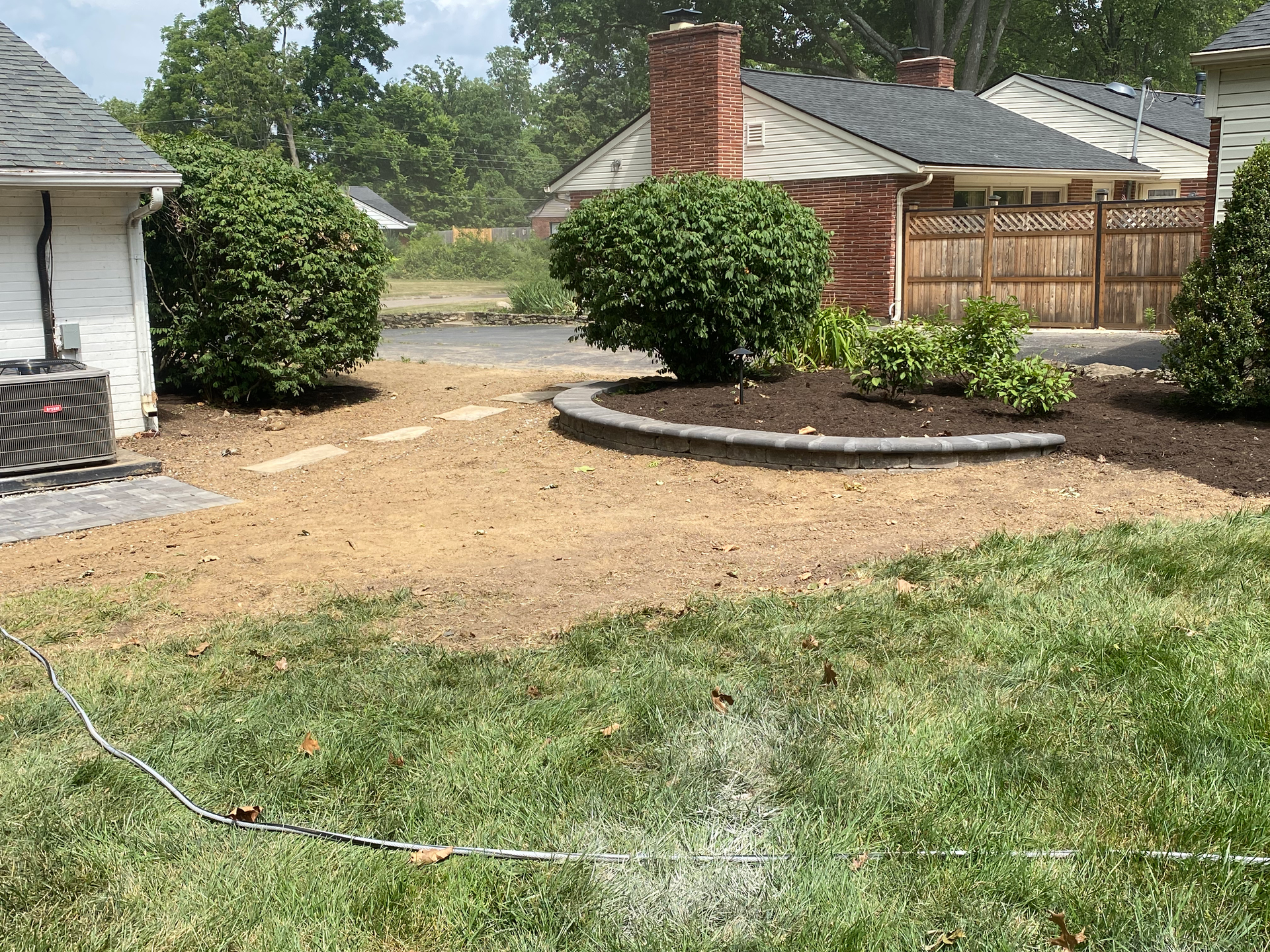 A sprinkler is spraying water on a lush green lawn in front of a house.