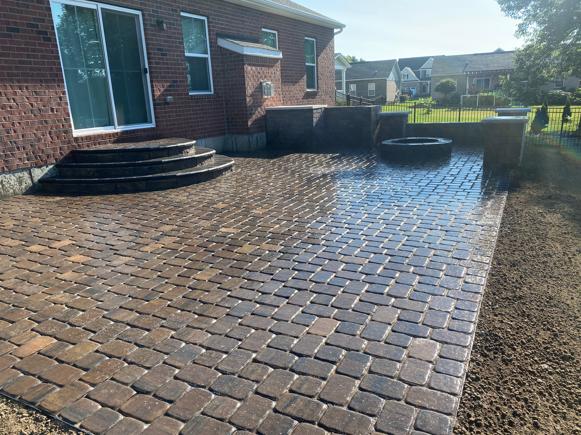 A brick patio with stairs and a fire pit in front of a brick house.