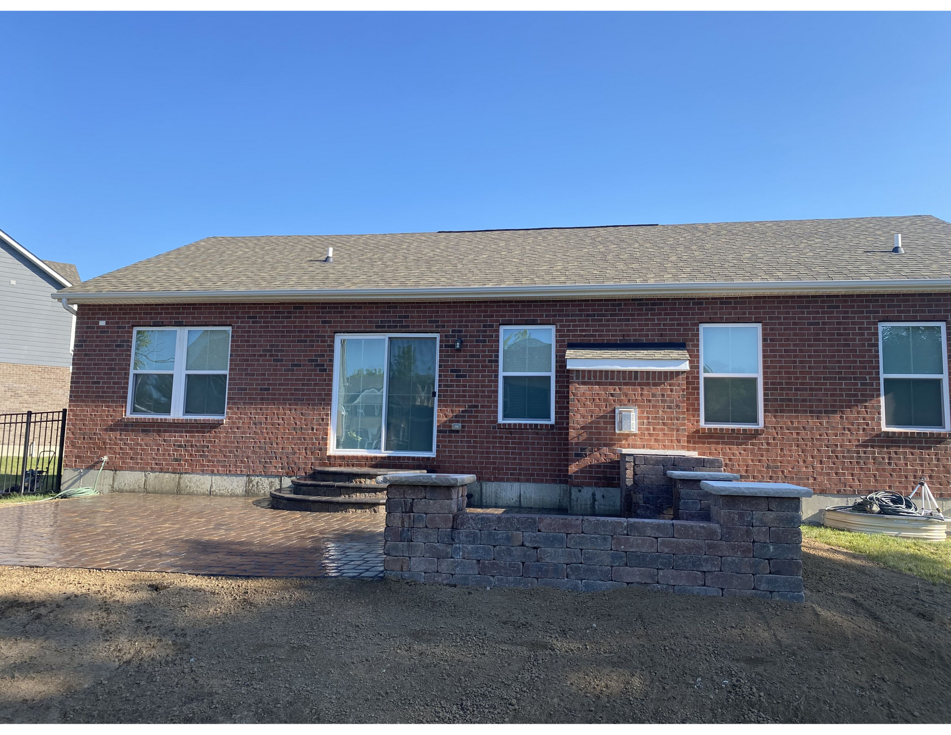 A brick house with a lot of windows and a patio in front of it.