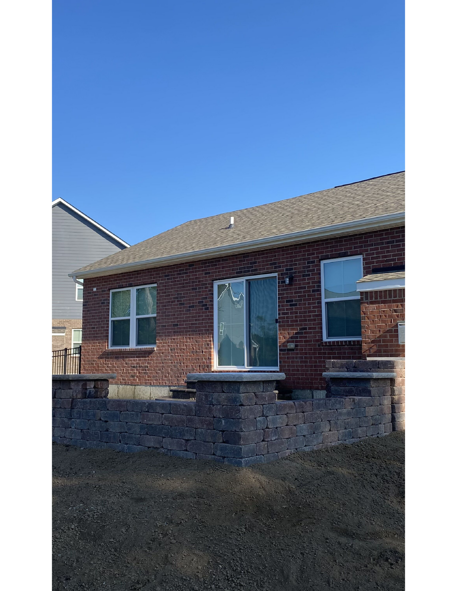 A brick house with a sliding glass door and a stone wall in front of it.