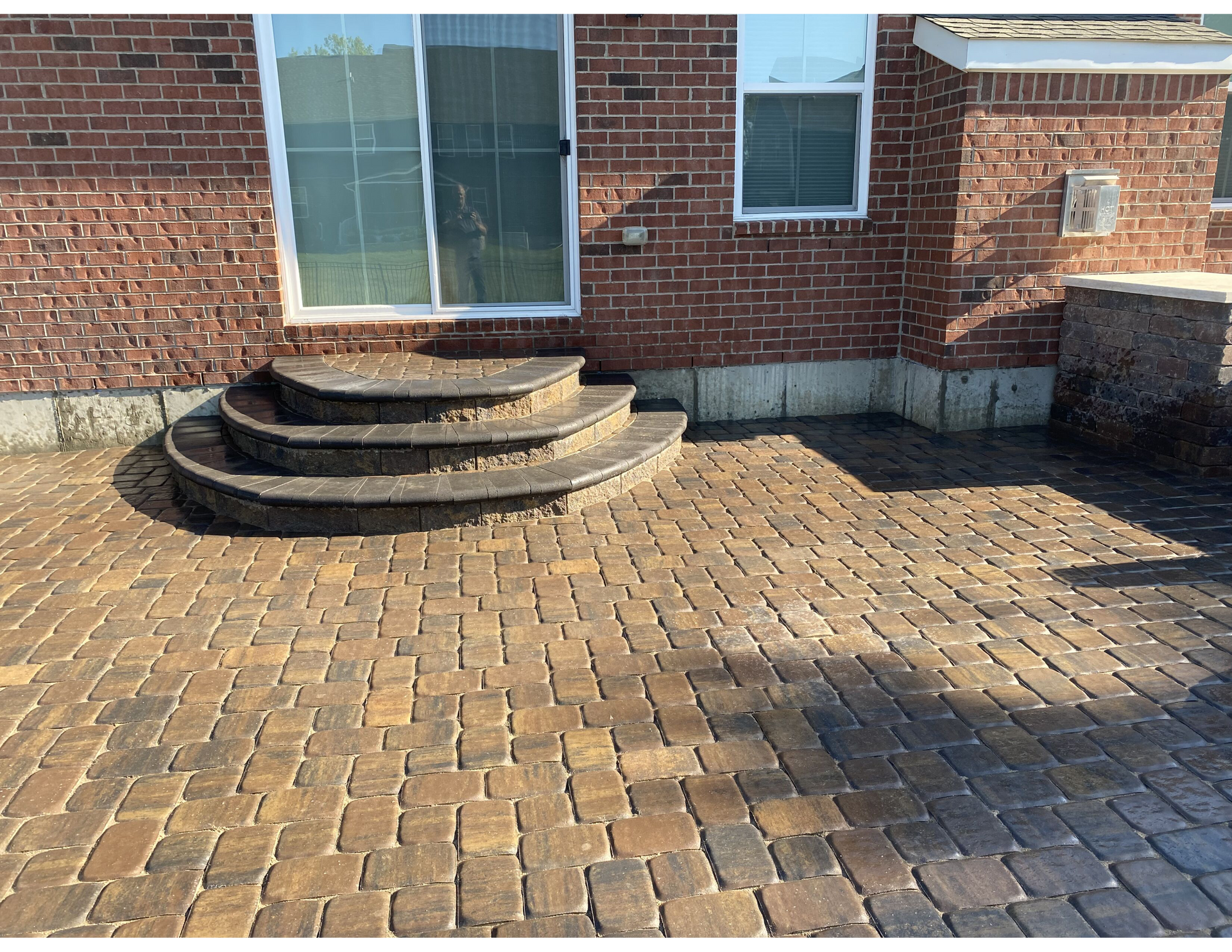 A brick patio with steps leading up to a brick house