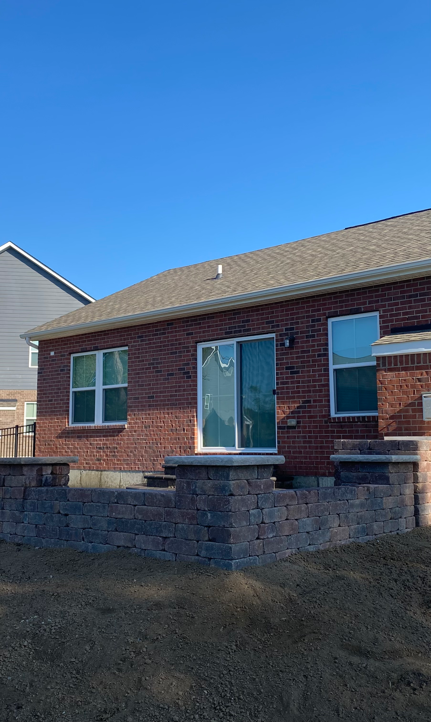A brick house with a sliding glass door and a stone wall in front of it.