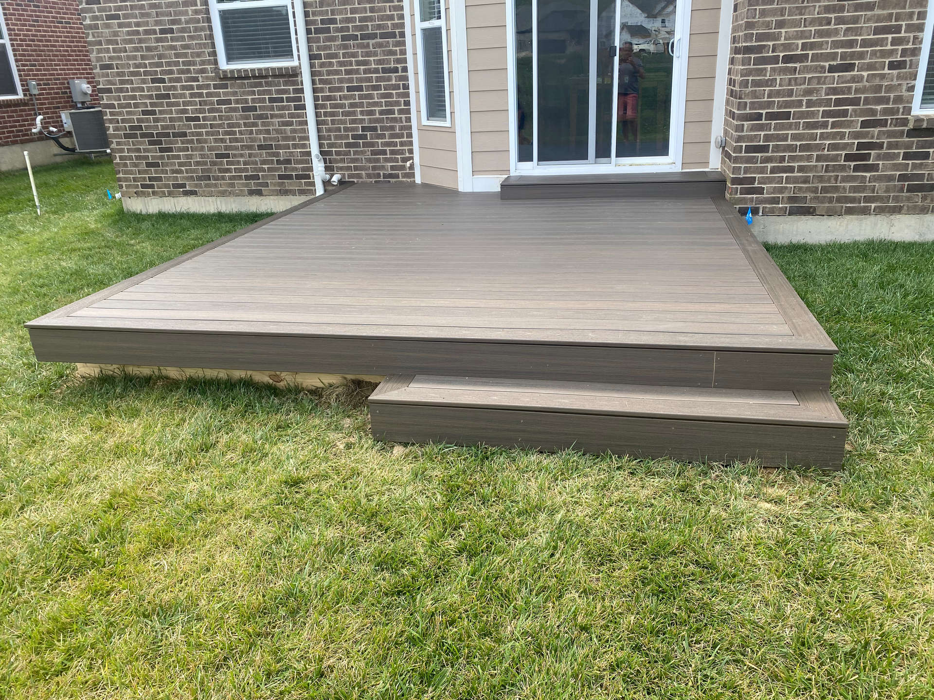 A wooden deck with stairs in front of a brick house.