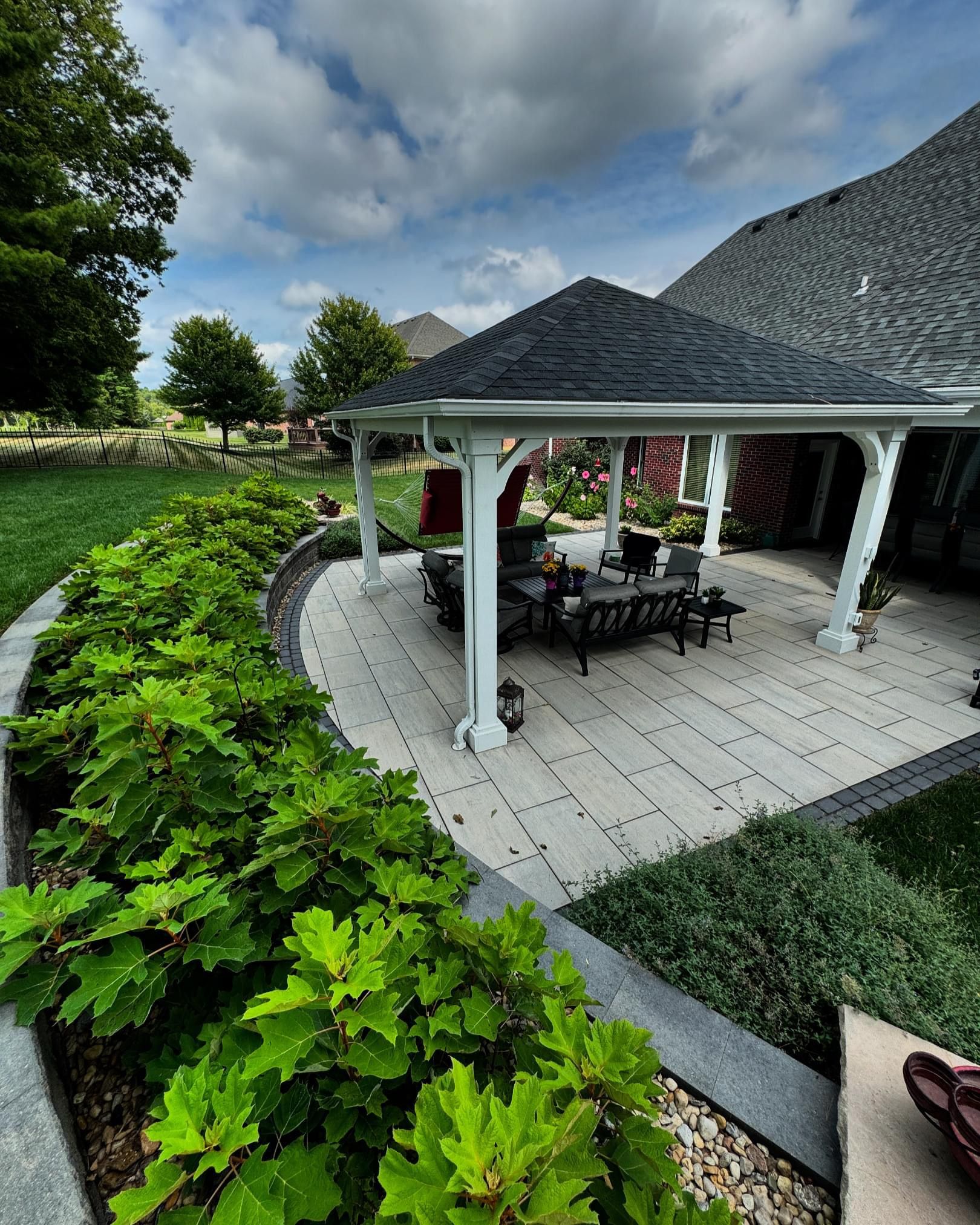 A patio with a pavilion and a table and chairs in the backyard of a house.