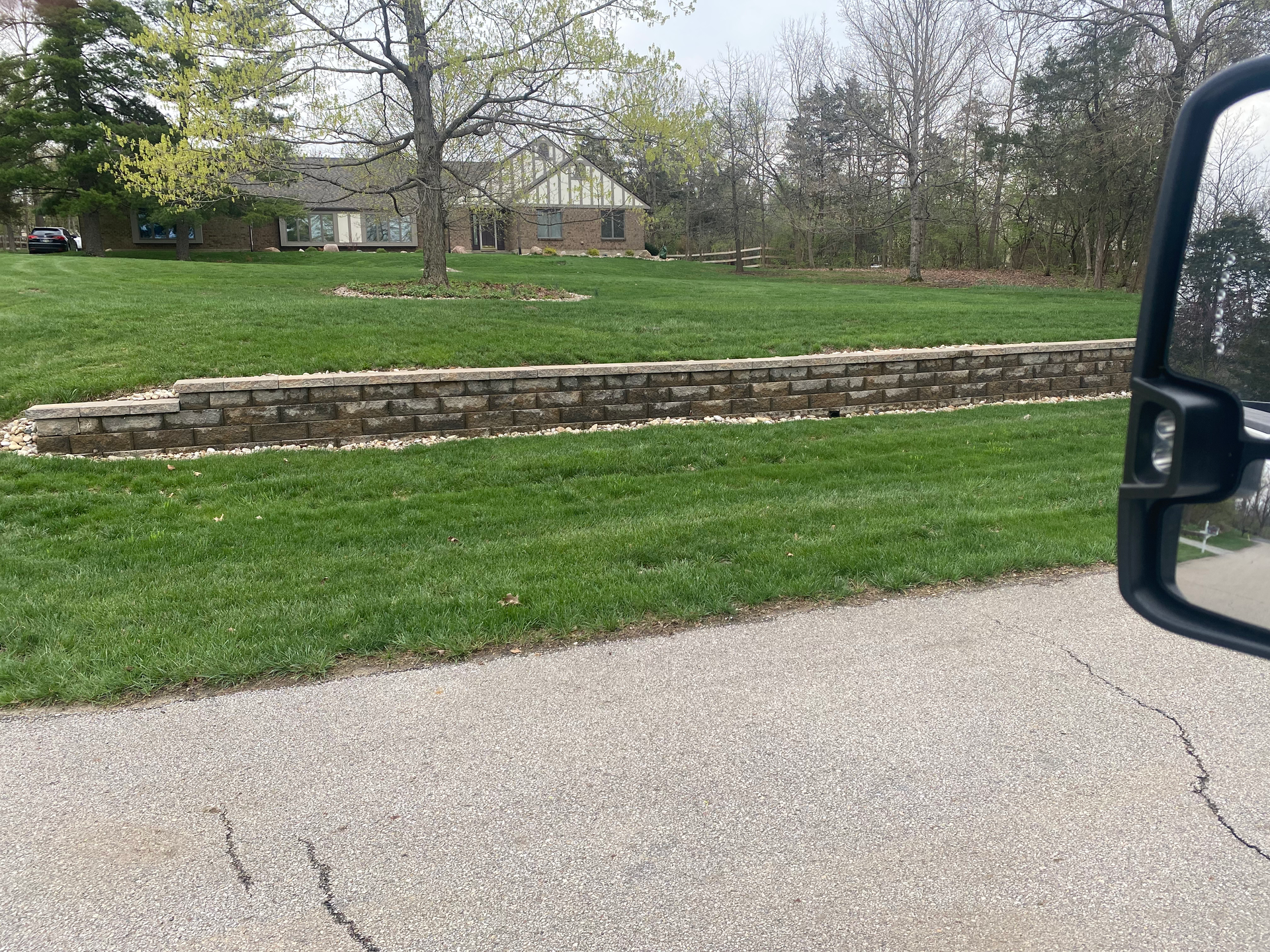 A truck is driving down a road next to a lush green field.