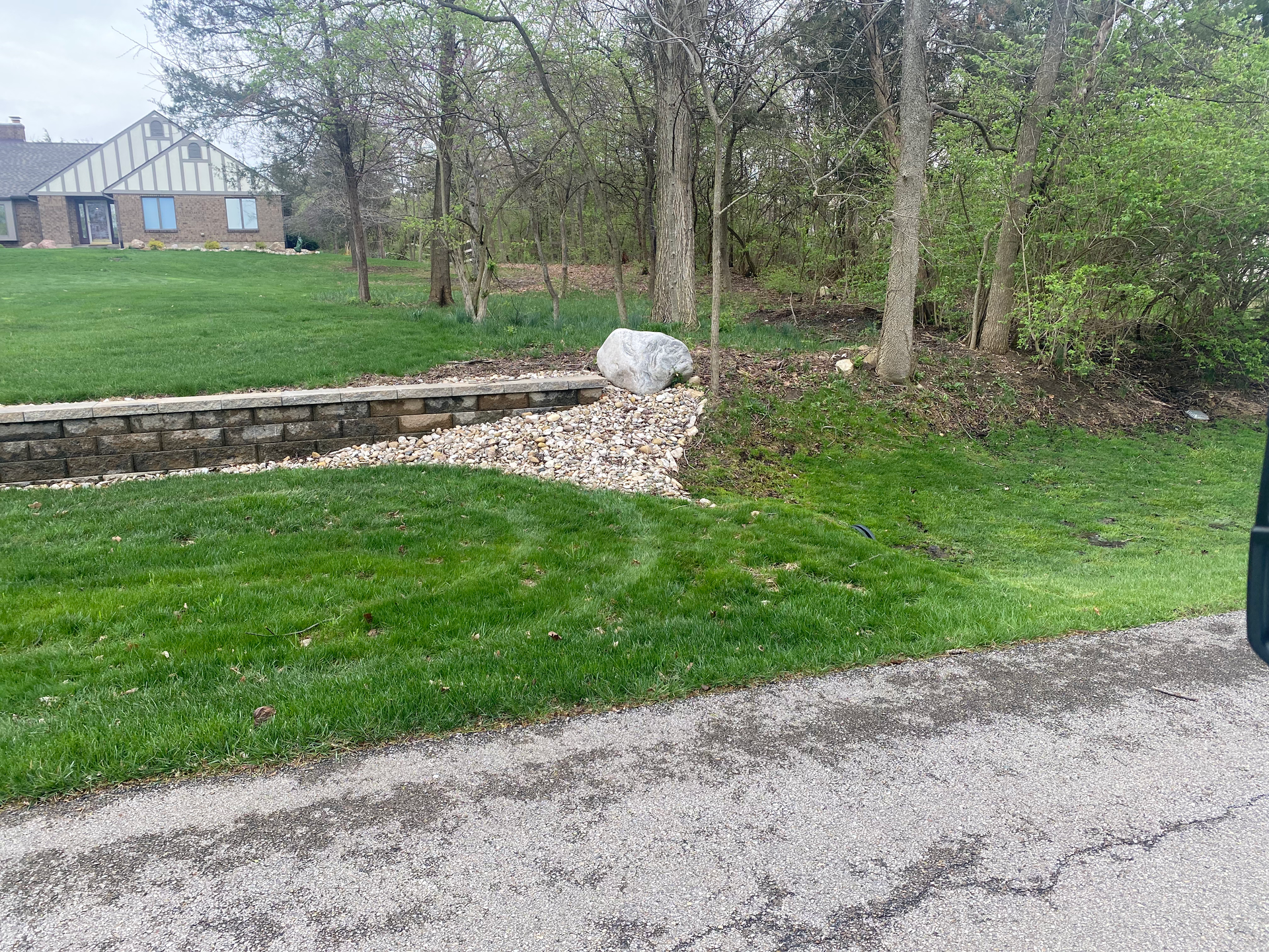 A driveway leading to a house with a lush green lawn and trees.