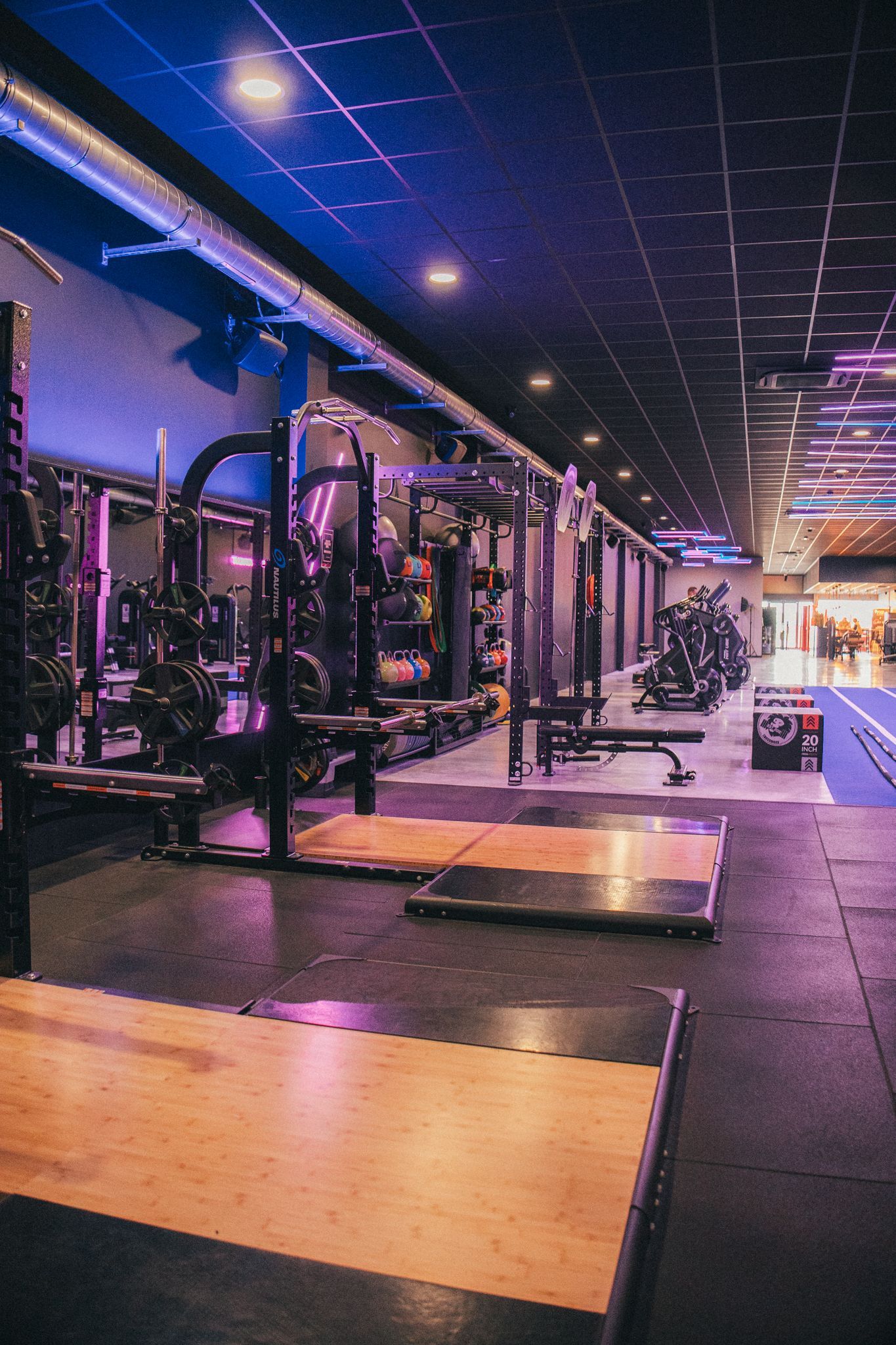Een gymzaal vol met fitnessapparatuur en een blauwe baan.
