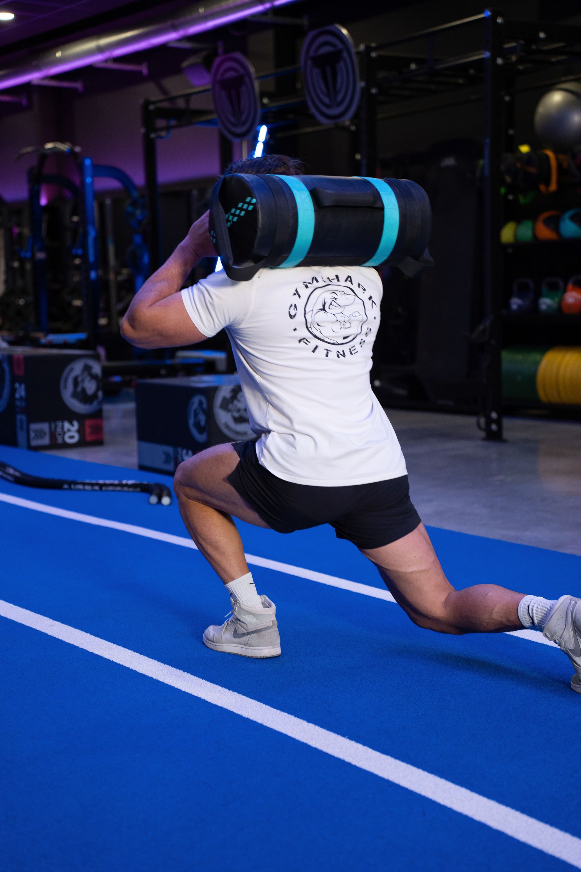 Een sportschool vol met fitnessapparatuur en een blauwe mat.