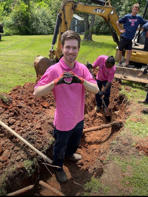 A white water heater is sitting in a room with pipes.