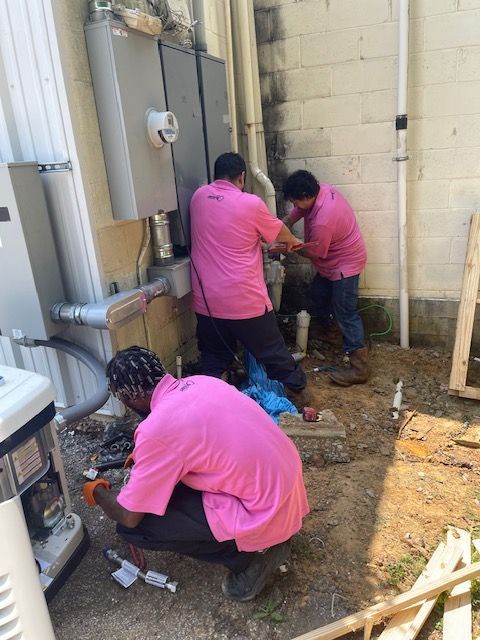 A group of men in pink shirts are working on a machine