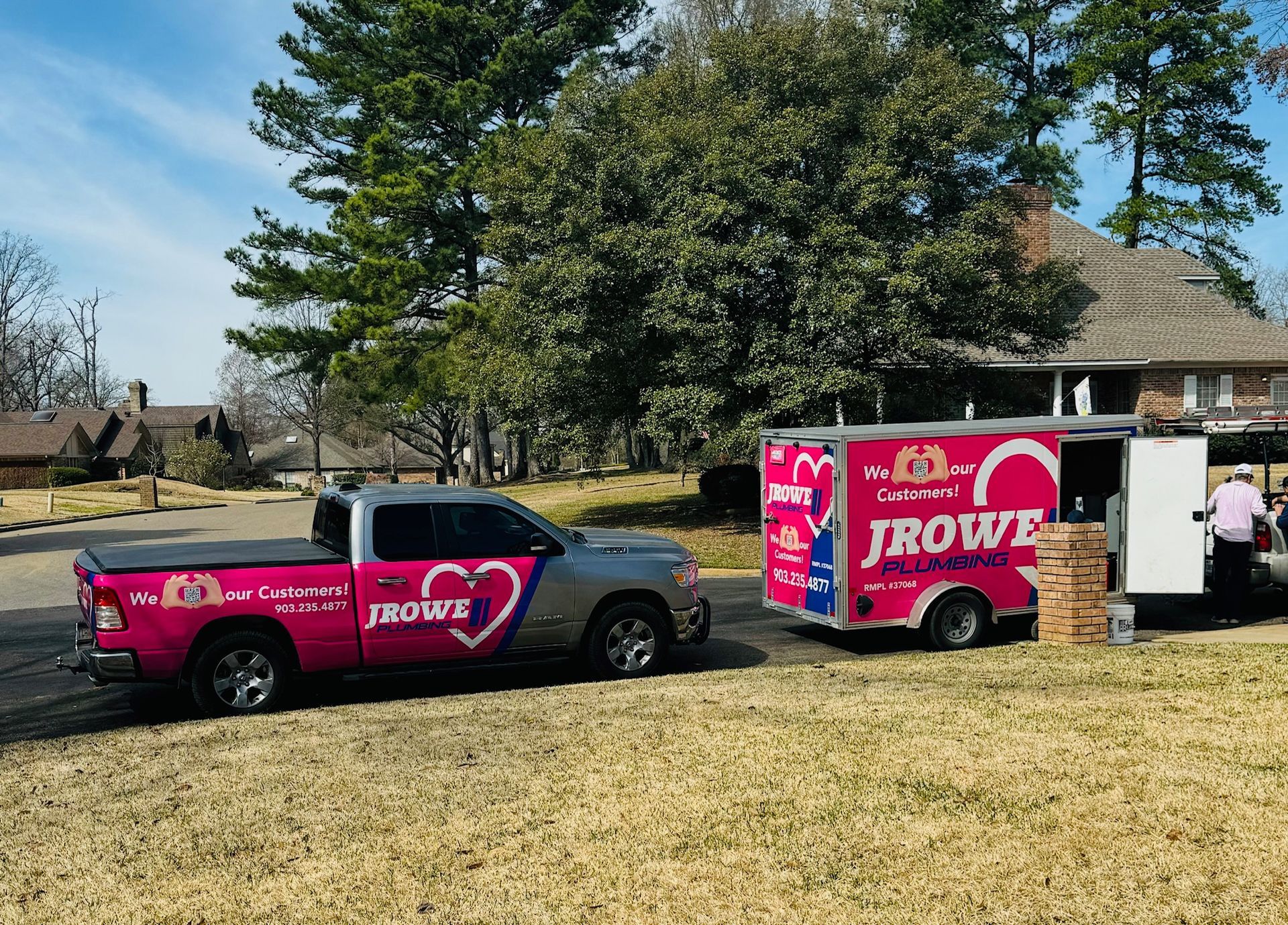 Two jbowe trucks are parked in front of a house.