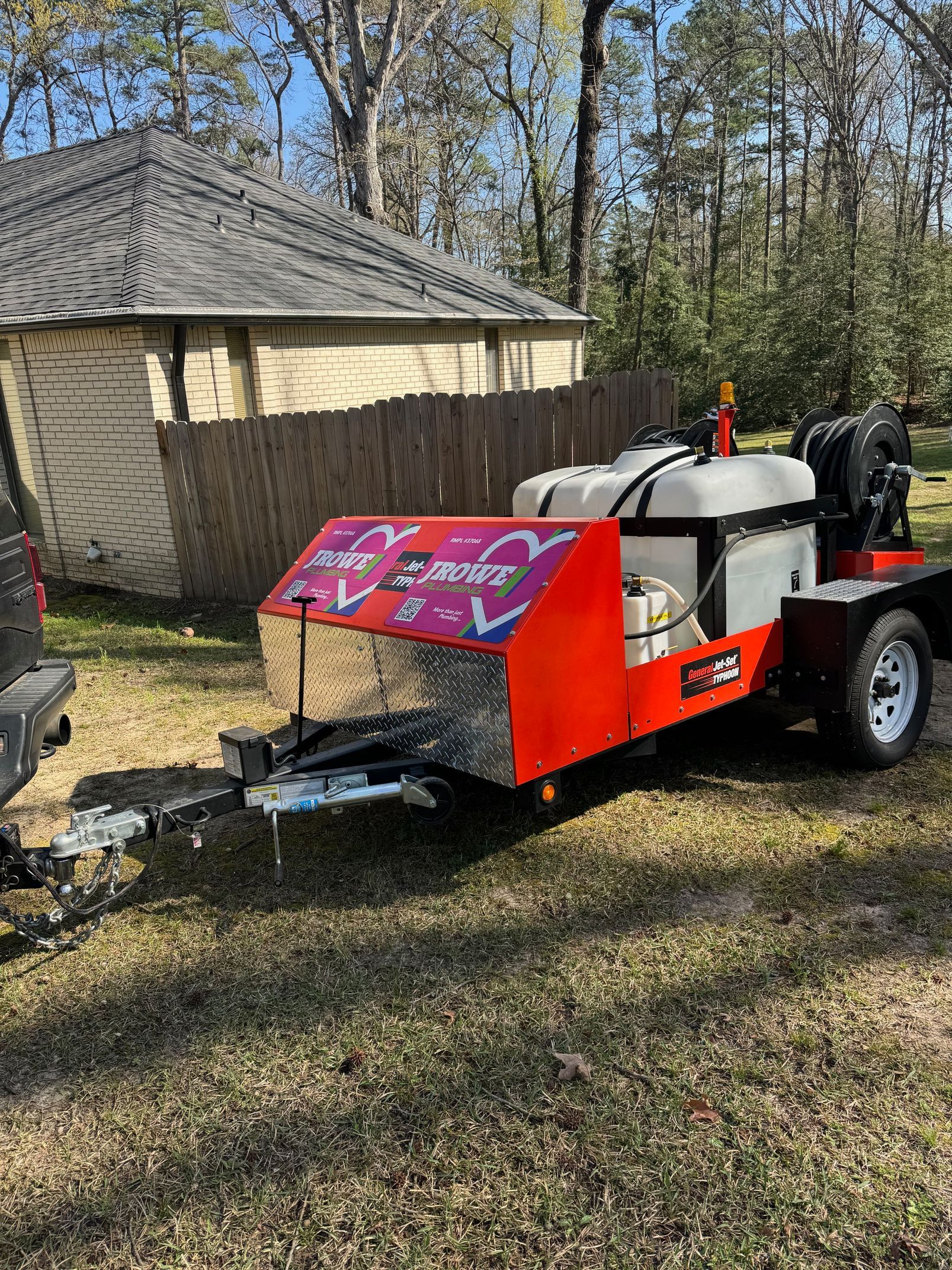 A red and white trailer is parked in front of a house.