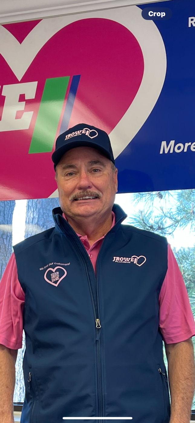 A man wearing a hat and a vest is standing in front of a heart.