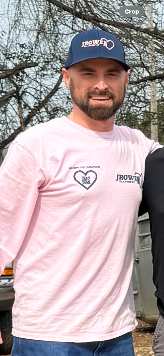 A man with a beard is wearing a pink shirt and a blue hat.