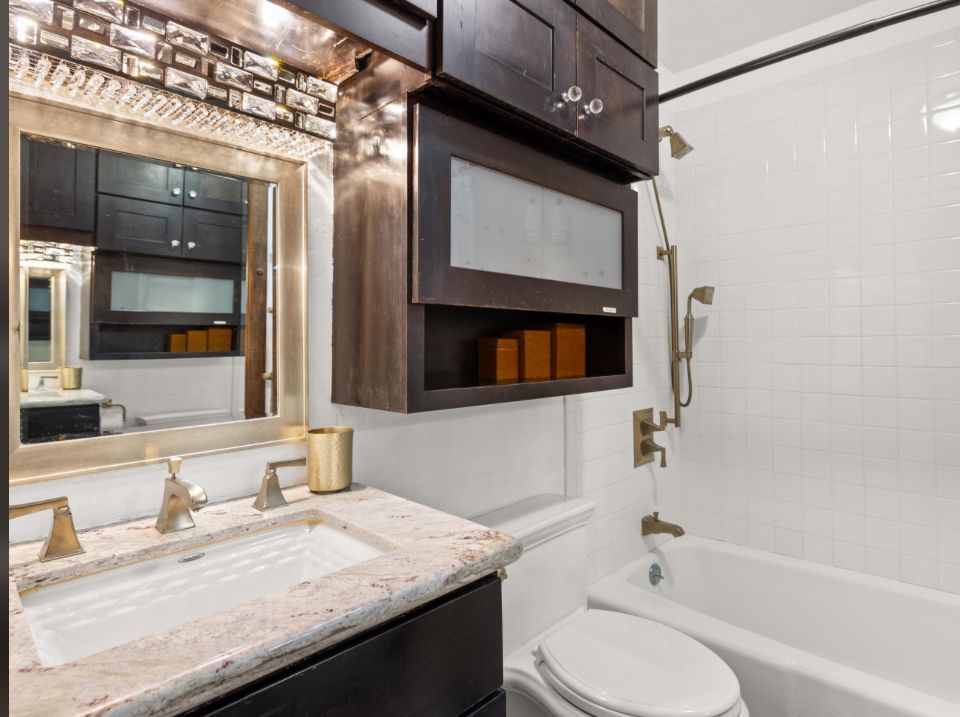 Small apartment with dark kitchen cabinets, brown sofa, and two chairs.