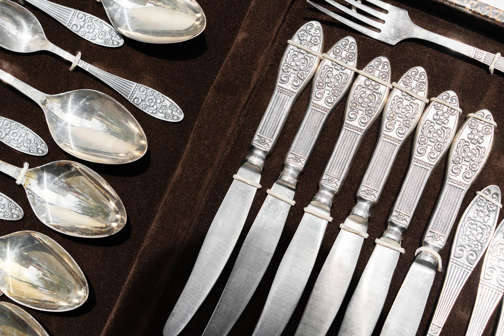 Silverware including knives spoons and forks on a brown cloth