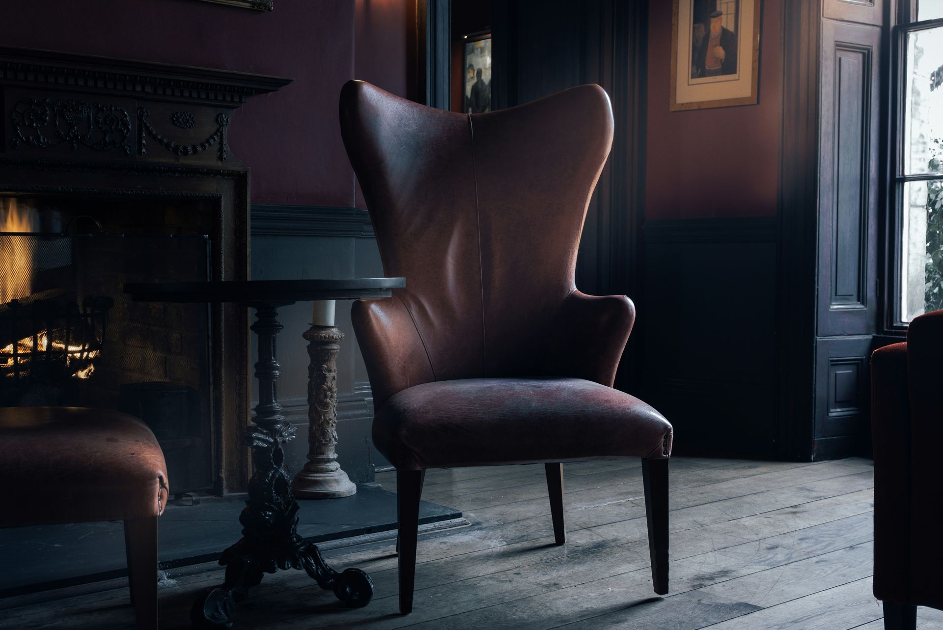 A chair is sitting in front of a fireplace in a dark room