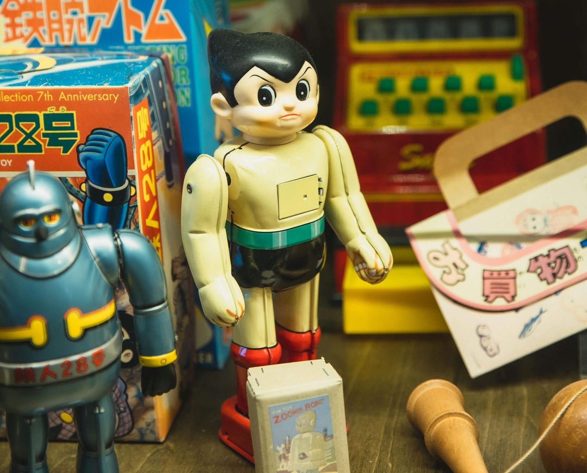 A toy robot is standing next to a box that says ' astro boy ' on it