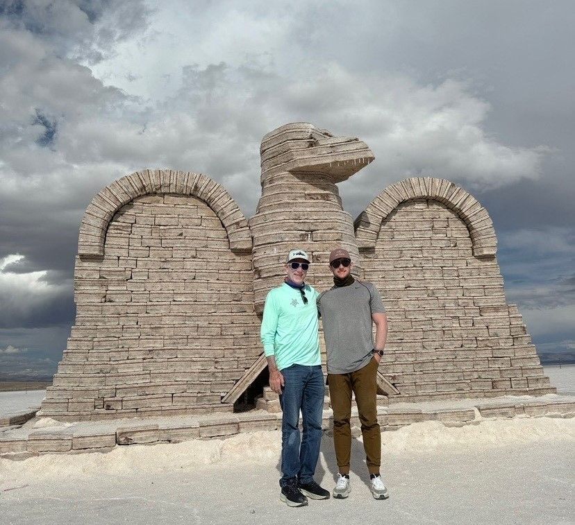 Two people standing in front of a large brick eagle sculpture