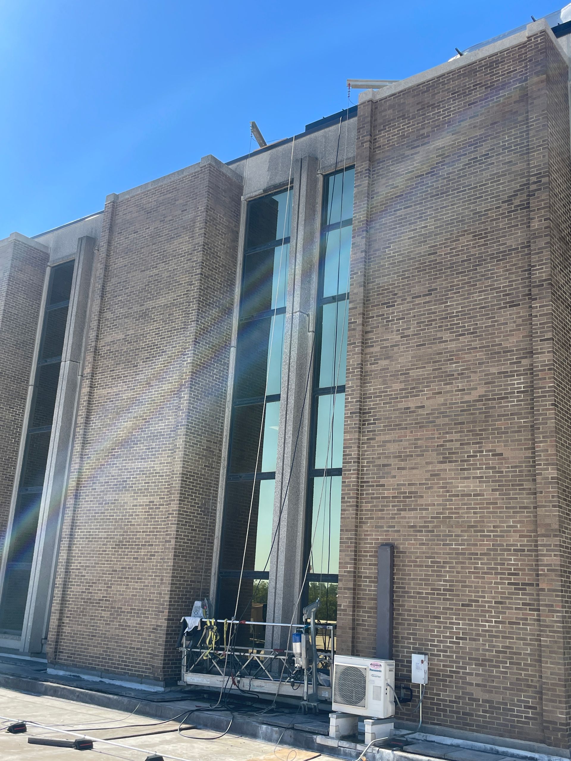A large brick building with a lot of windows is under construction.