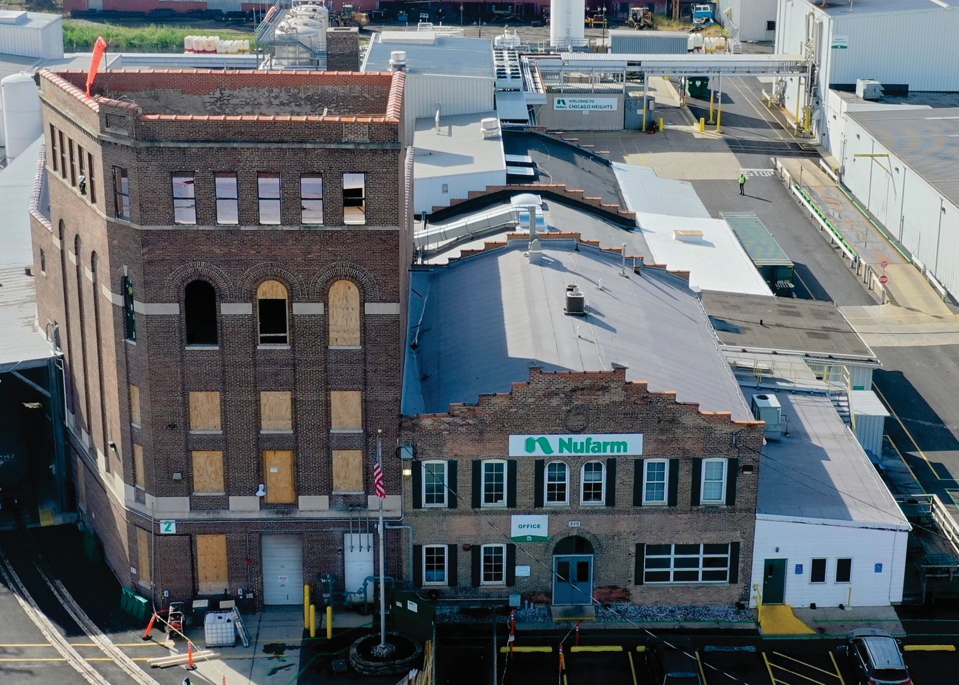 An aerial view of a brick building with a green sign that says NuFarm on it