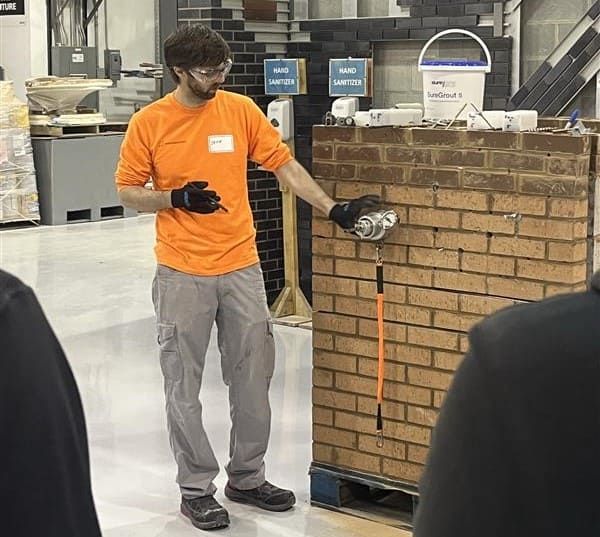 Instructor demonstrating spiral tie pull testing on a masonry mockup during hands-on training