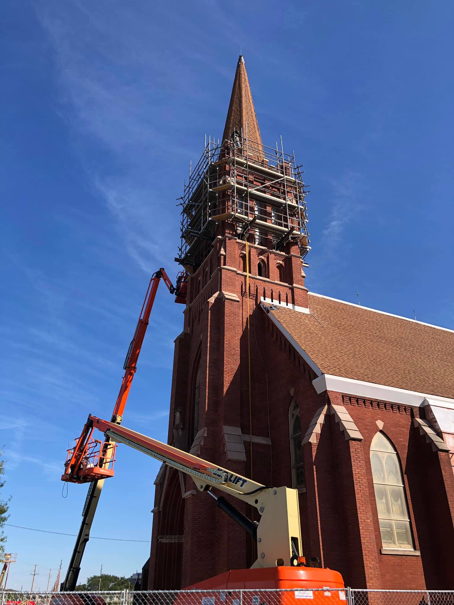 A large brick church with a steeple is being restored.