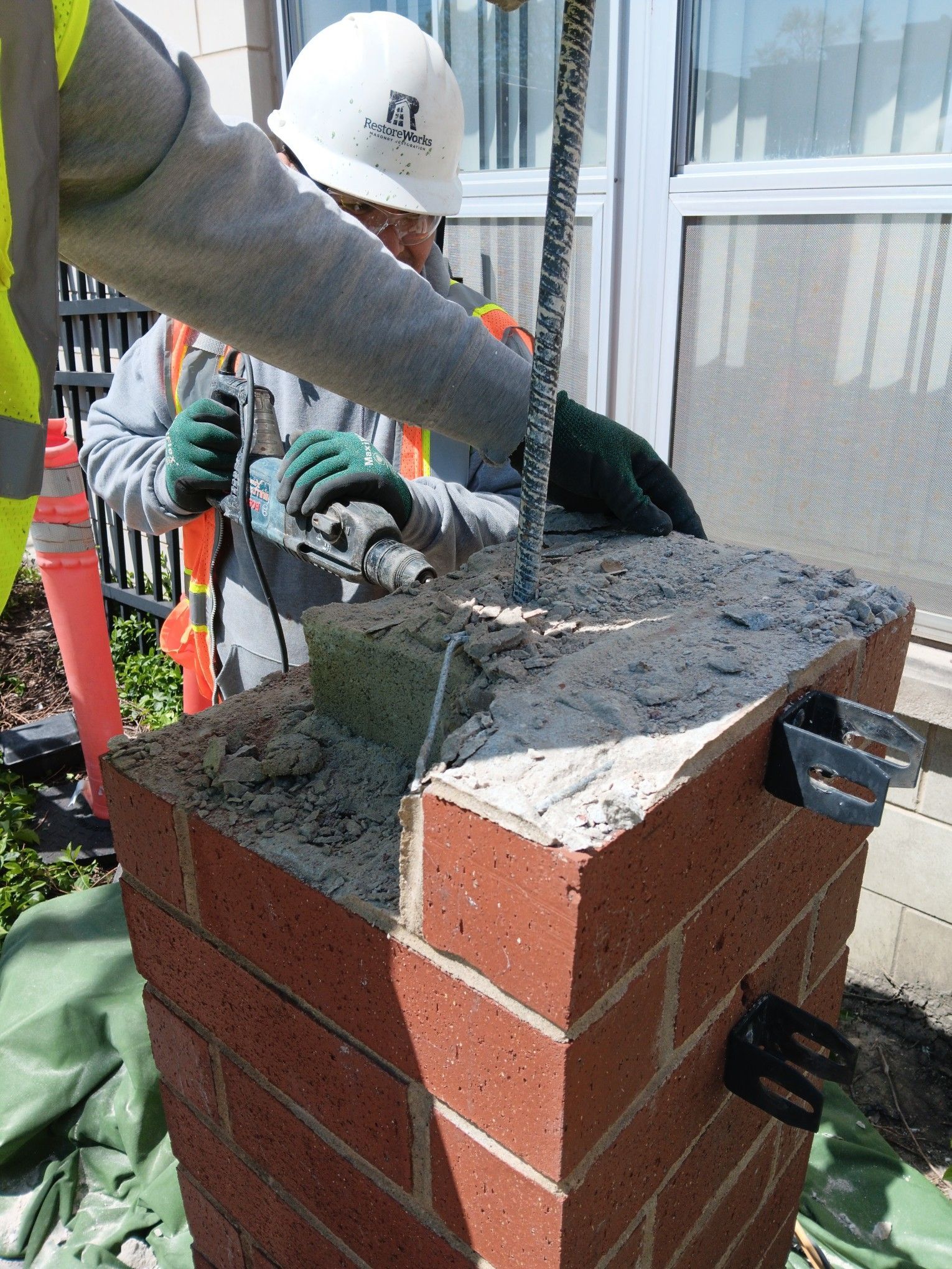 A man wearing a hard hat is working on a brick pillar at Churchview Living