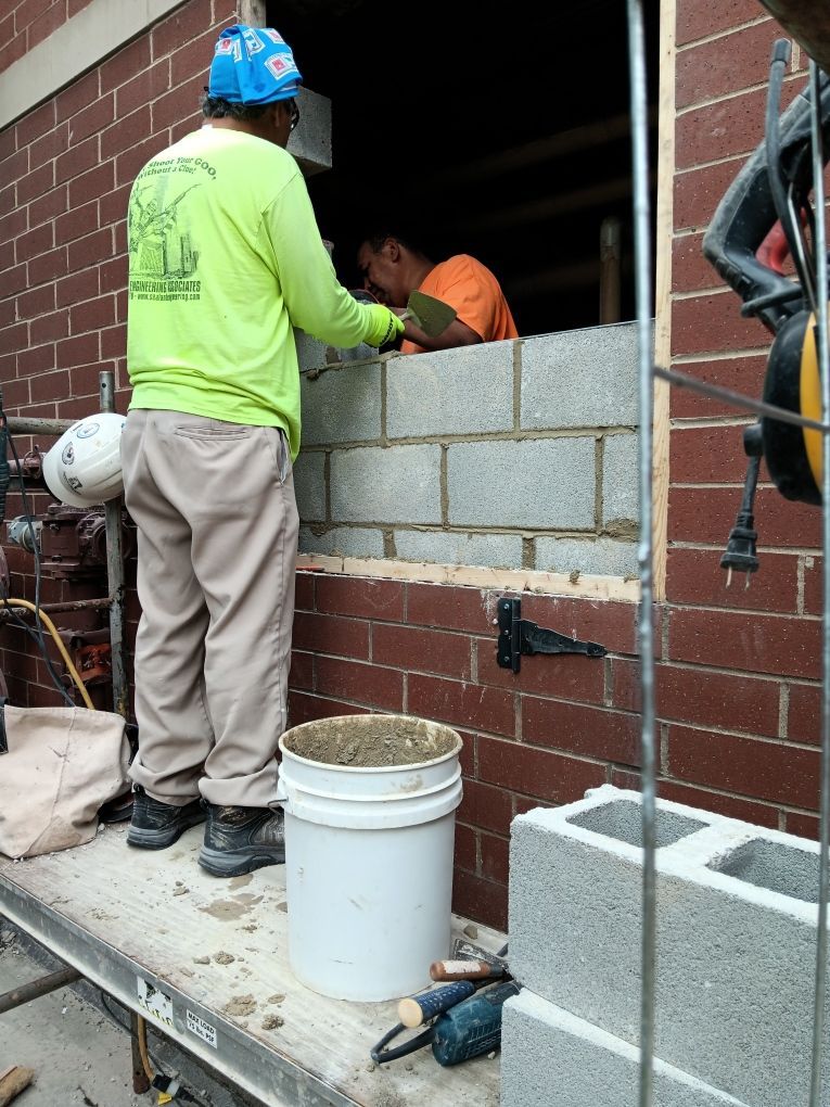 A man in a neon green shirt is working on a brick wall at Churchview Living