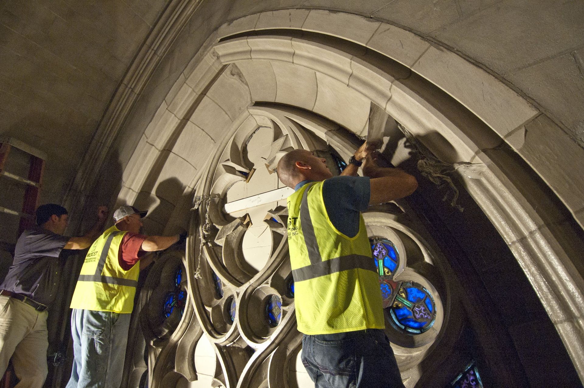RestoreWorks team restoring interior stonework around a stained-glass window at Duke University Chapel.