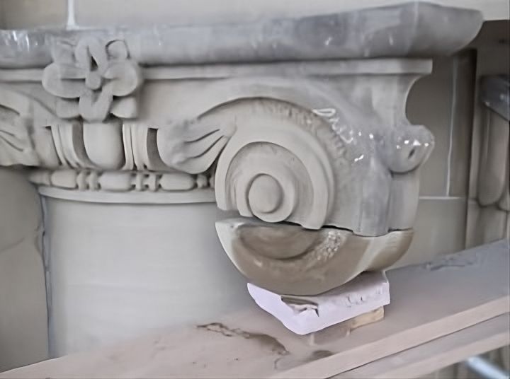 Dutchman stone repair in progress on an ornamental capital, showing a precisely cut replacement piece aligned to match the original profile and carved detail of the historic masonry element.