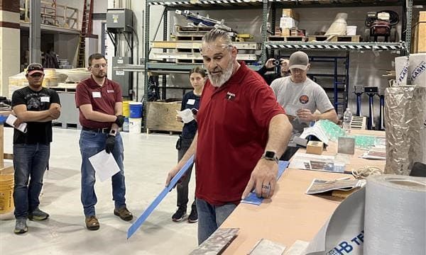 Instructor demonstrating flashing membrane installation during a hands-on masonry workshop
