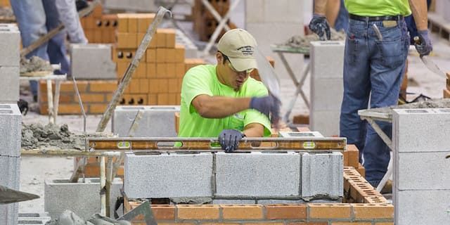 Union craftworker receiving hands-on masonry training at the International Masonry Institute, practicing bricklaying and blockwork techniques essential for building envelope restoration and repair.
