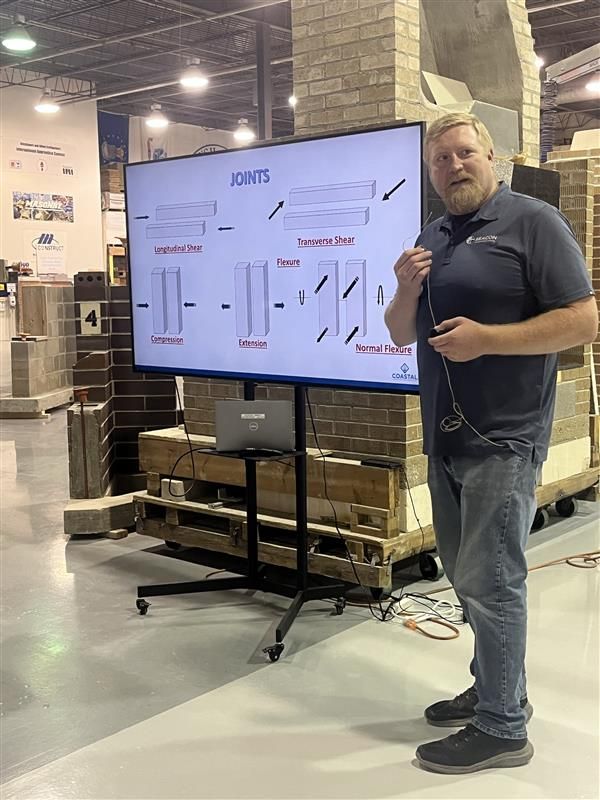 A man is standing in front of a large screen in a warehouse.