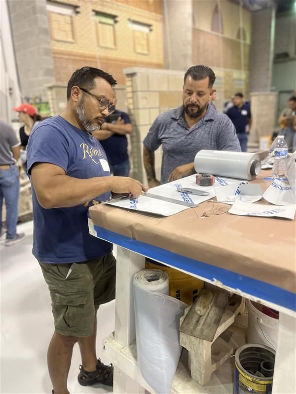 A man is standing at a table looking at a clipboard at IMI Workshop