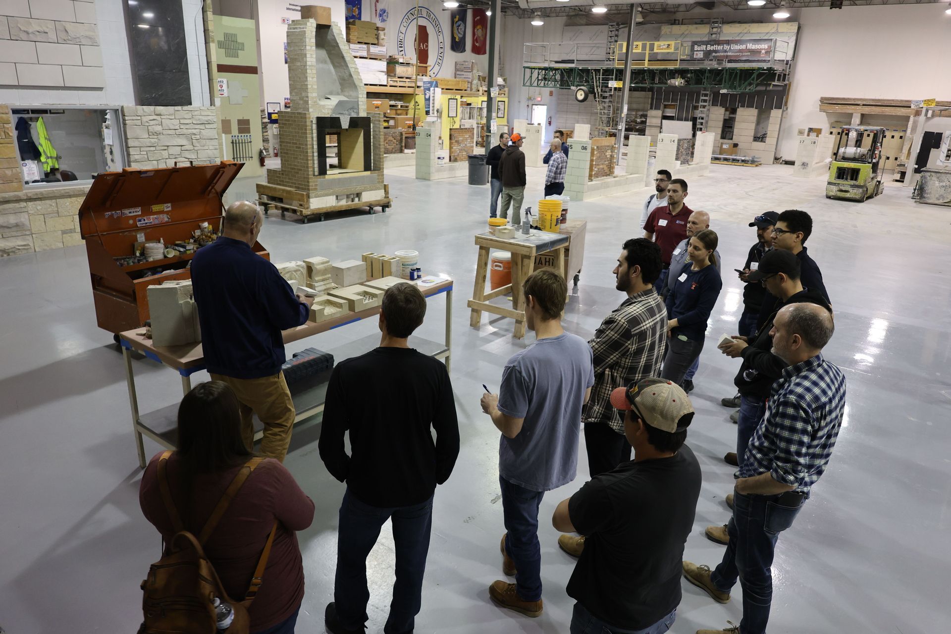 A group of people are standing in a warehouse looking at a machine.