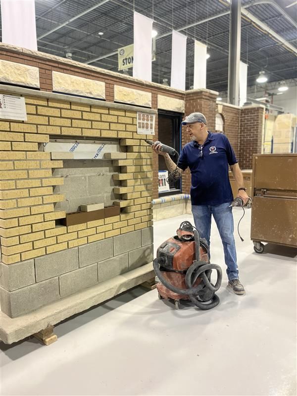 A man is standing in front of a brick wall with a hop vac at IMI Workshop