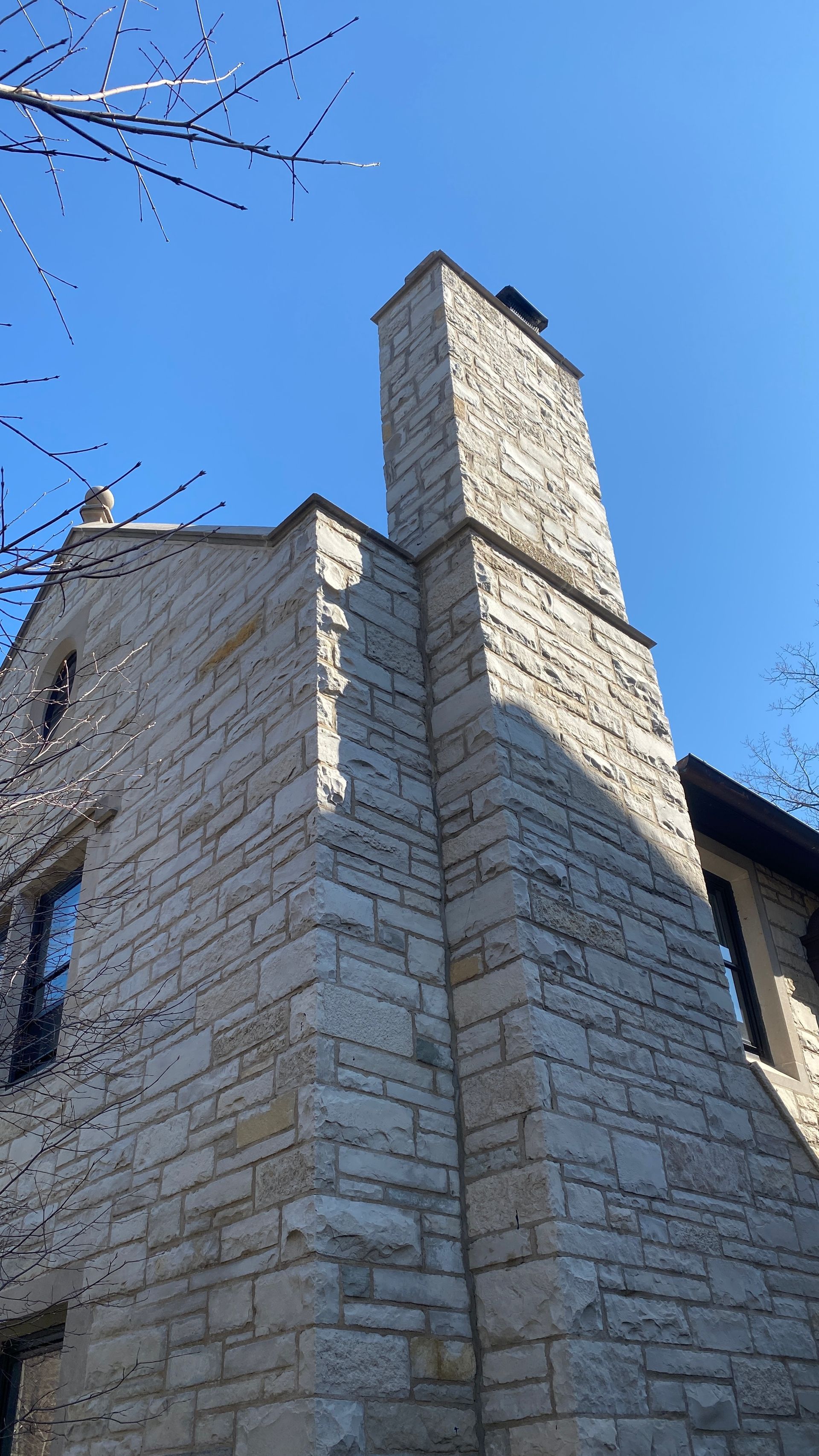 A luxury home with a stone chimney on the side of it.
