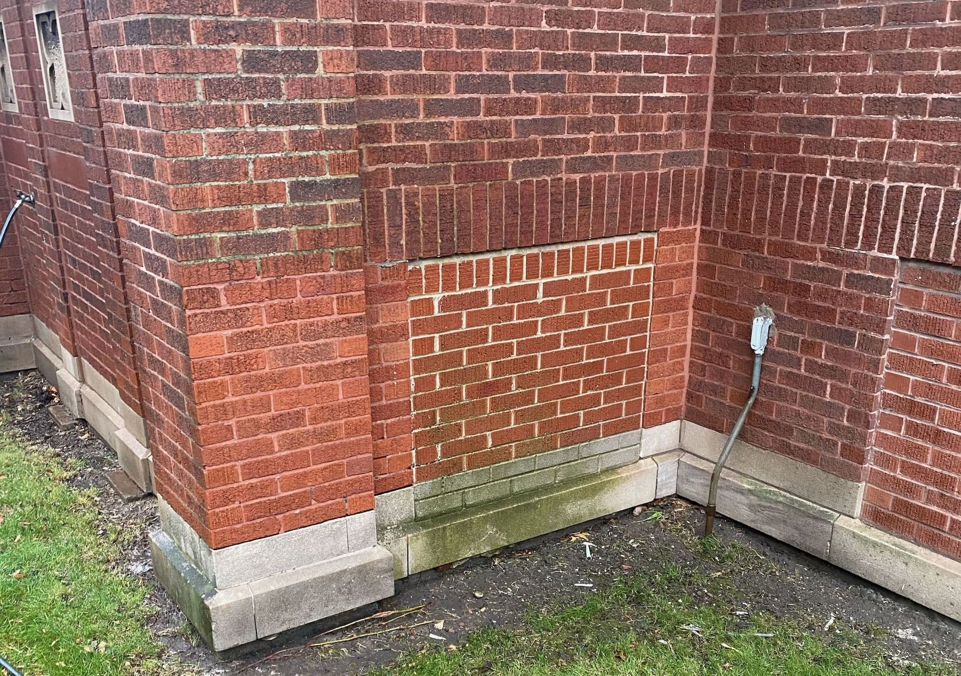 RestoreWorks cleaning mock-up on a brick façade showing damp areas, remaining biological staining, and tonal contrast with uncleaned adjacent masonry, illustrating normal early-stage conditions in restorative cleaning.