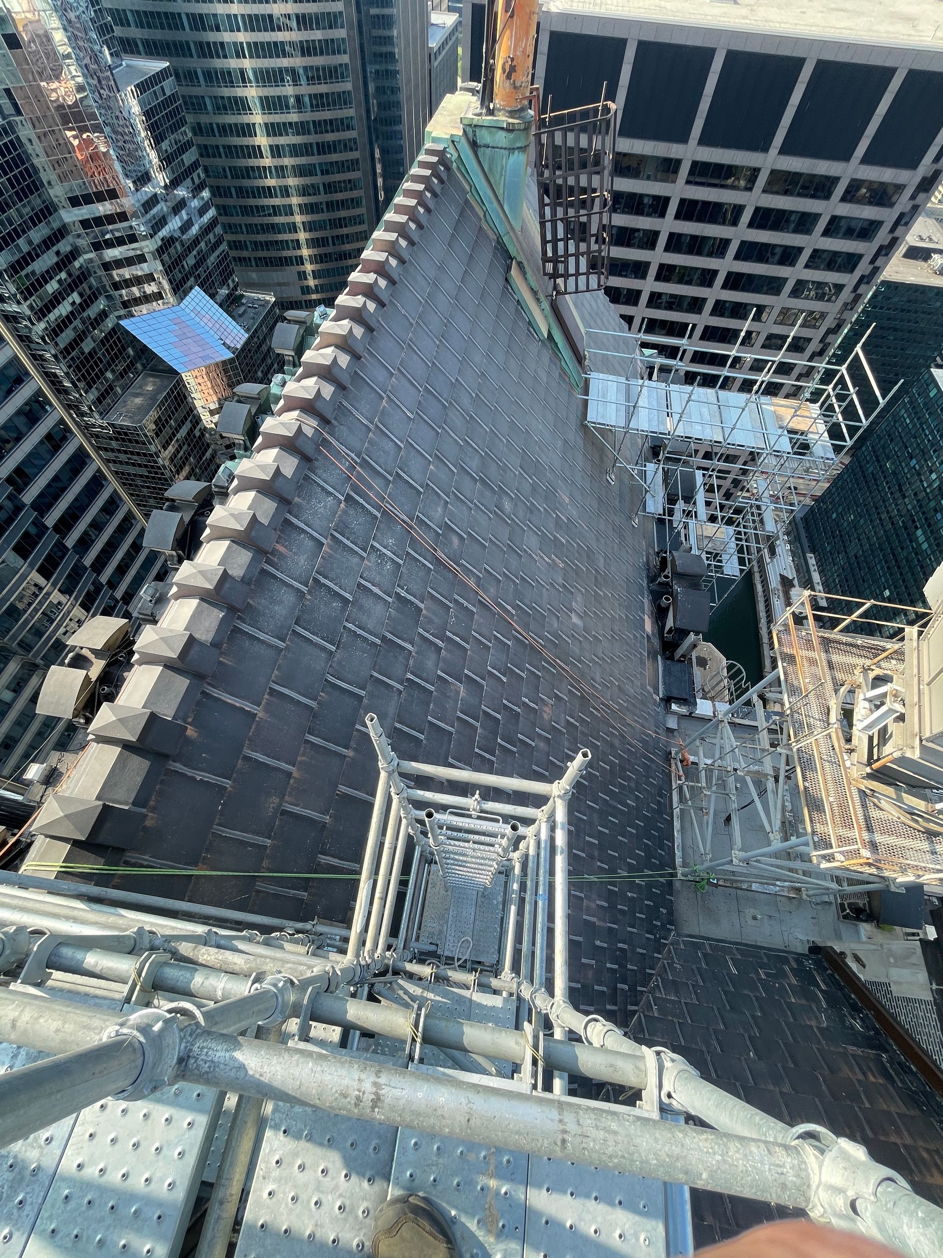 A person is standing on top of a scaffolding on the Civic Opera House looking down at a city.